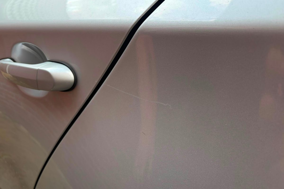 Silberne Fahrzeugtür mit oberflächlichem Kratzer vor der Behandlung